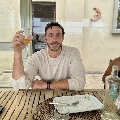 Michael Rode seated at an outdoor table, raising a glass
